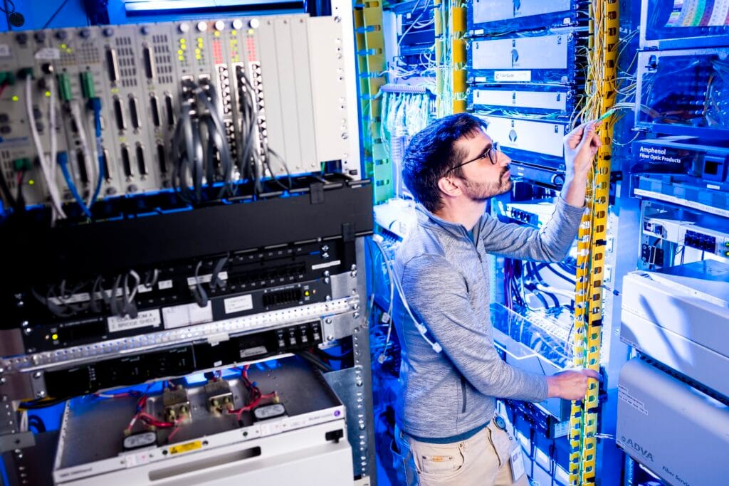 NextLight 801 803 ONT self install guide with a network technician managing Ethernet and fiber patch cables in blue-lit server racks.